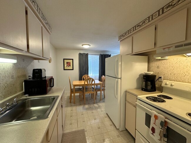 Full kitchen with large sized refrigerator, four burner stove and all dining & cookware - Avalon Apartments