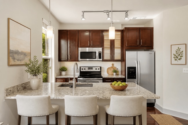 A kitchen with a granite countertop and white chairs. - ICON at Dulles