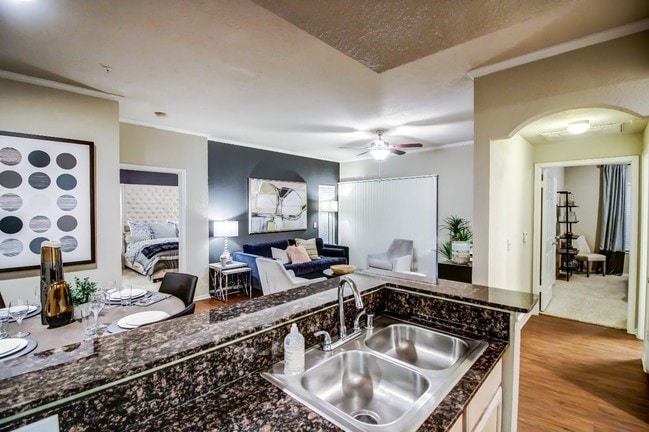 Kitchen are and living room with cozy dining nook, double sink and hardwood style flooring - Colonnade at Willow Bend