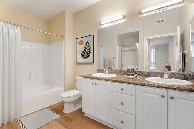 Renovated Package I bath with beige speckled granite countertop, white cabinetry, and hard surface flooring - Avalon Glendale