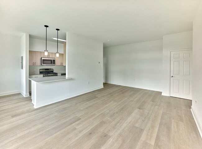 Open-concept floor plan with modern kitchen and wide plank flooring at Crestwood Apartments in Wayne, PA - Crestwood