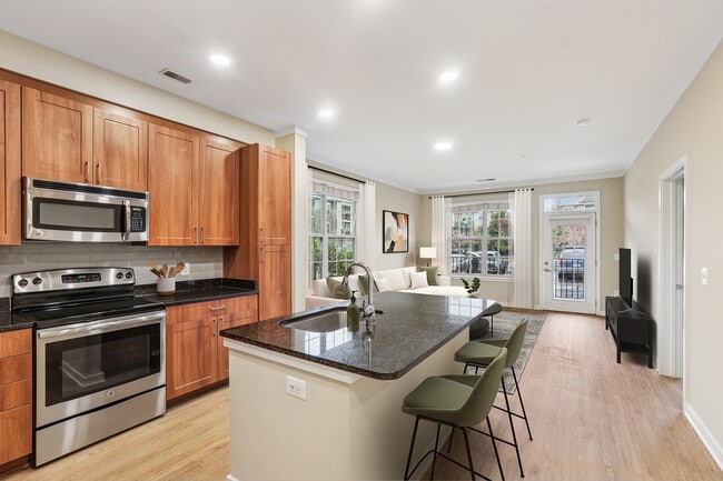 Updated Finishes kitchen with stainless steel appliances, grey tile backsplash, granite countertops, and new hard surface flooring and lighting - Avalon Falls Church