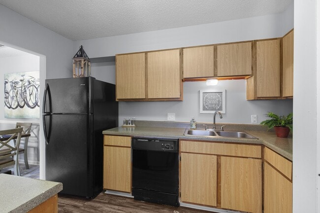 Sleek, matching black appliances and warm wooden cabinetry come together in the kitchens at Lakeland East Apartments in Flowood, MS. Managed by Highlands Vista Group. - Lakeland East