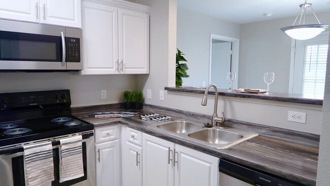 Revel in premier kitchens boasting black fusion granite-inspired countertops and modern white cabinetry for a chic culinary experience. - Lenox West Luxury Apartments