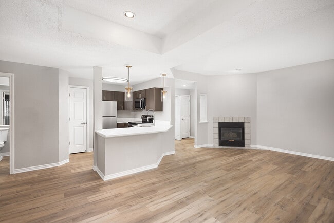 Modern apartment kitchen with elegant white countertops, stainless steel appliances, and warm wood flooring. - Avana Belmar