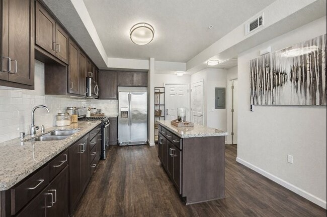Aspire Apartments Tracy CA A modern kitchen with dark wood cabinets and stainless steel appliances. - Aspire Apartments