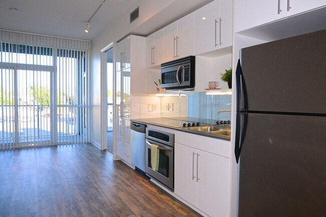 Kitchen with hardwood floors, stainless steel apliances and  patio access at 12th Street Lofts in National City, California. - 12th Street Lofts