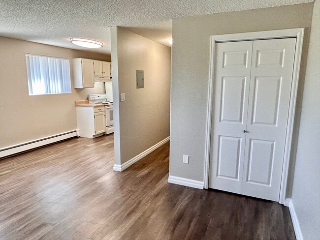 Inviting apartment interior with modern laminate flooring, compact kitchen featuring white cabinetry, and bright natural light. - 5351 Delaware