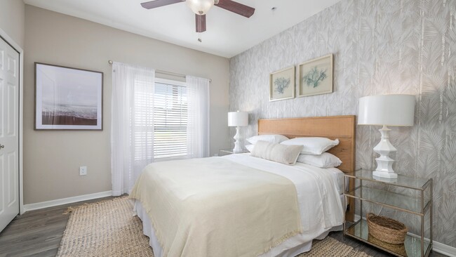 Step into the lap of luxury in our spacious master bedroom, graced with wood-style flooring and a majestic ceiling fan that's fit for royalty. Unwind in style and comfort. - Banyan Bay