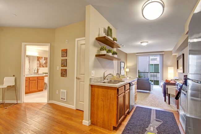 An open kitchen with stainless steel appliances and shelving with a view through to the living area - The Artiste