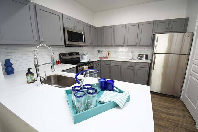 Kitchens feature stainless steel appliances and gray or white shaker-style cabinets and countertops - NoA on McNeil Townhomes + Flats