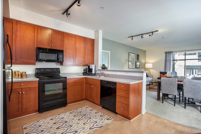 Classic Package I kitchen with black or white appliances, cherry cabinetry, laminate countertops, and hard surface flooring - Avalon at Cahill Park