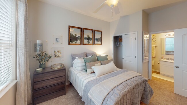 A cozy bedroom at Ralston Apartments in Downtown Indianapolis, featuring soft décor, plush bedding, and an ensuite bathroom with modern finishes. - Ralston Apartments