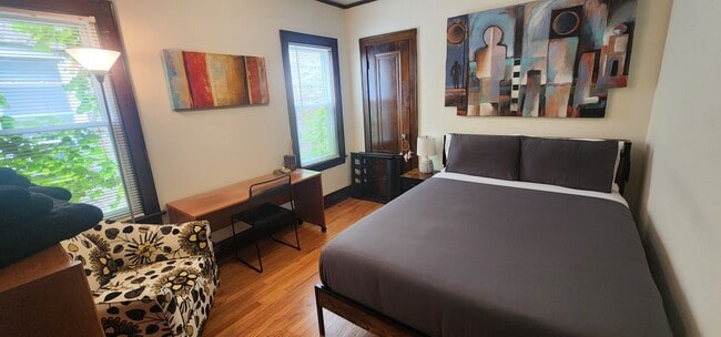 Third Bedroom with LED Queen bed, nightstand, desk and chair, accent chair, file cabinet, and shelf. - Lake Street Penthouse