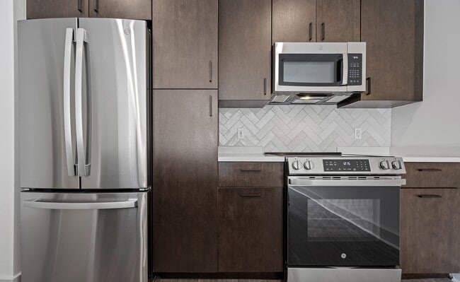 Herringbone tile runs the full height between the counter and the upper cabinets. - The Landing at Vinnin Square