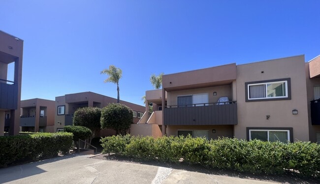 Private patios and balconies amongst manicured bushes and trees at Villa Pacific Apartments in Oceanside, California. - Villa Pacific Apartments