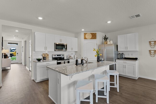 Modern kitchen with island seating, granite countertops, and stainless steel appliances. - Cedar Ridge