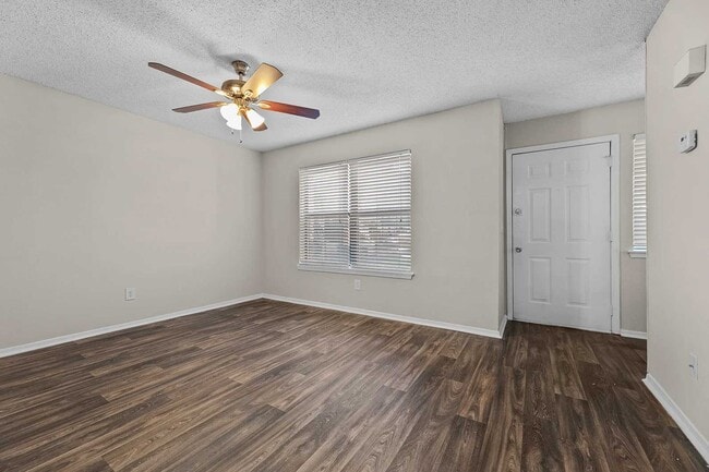 Vacant bedroom with dark wood-look vinyl flooring, ceiling fan with light, window with blinds, and white closet door - Walnut Creek