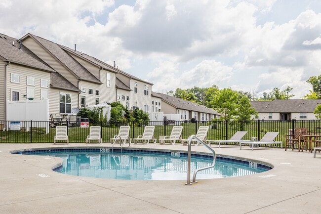 Dive into relaxation at our sparkling pool, surrounded by comfortable lounge chairs and scenic apartment views. - Wheaton Village Apartments