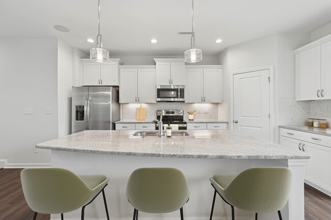 Upgrade Package kitchen with white cabinetry, designer tile backsplash and undercabinet lighting, and granite countertops - Avalon Townhomes Brier Creek
