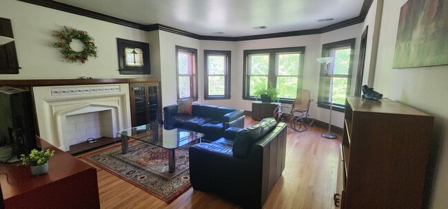 Living Room with leather sofa and armchair, antique rocking chair, large TV, floor lamps, & credenza - Lake Street Penthouse