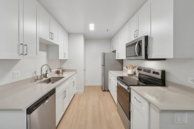 Renovated Package I kitchen with white cabinetry, grey quartz countertops, stainless steel appliances, and hard surface flooring - Avalon Mountain View