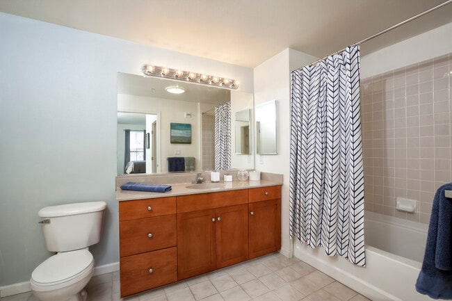 Classic Package I bath with cherry cabinetry, laminate countertops, and tile flooring - Avalon at Cahill Park