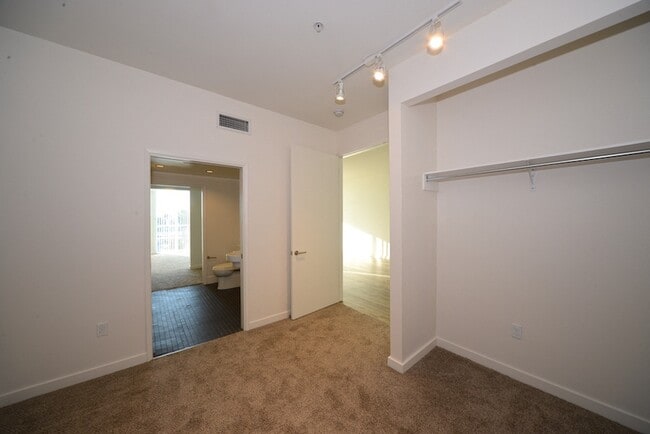 Carpeted bedroom with spacious closets and shared bathroom at 12th Street Lofts in National City, California. - 12th Street Lofts