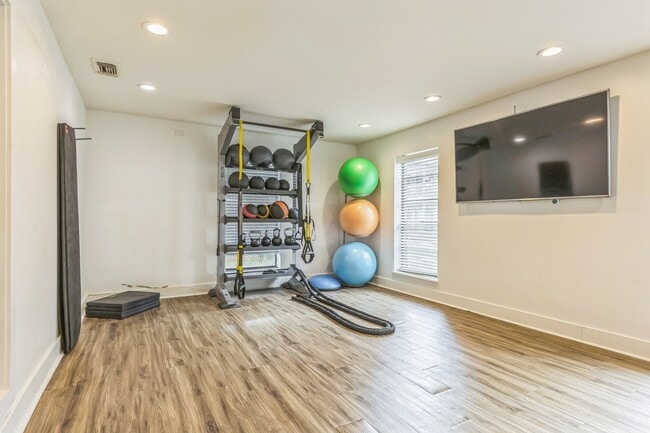 Enjoy varied workouts with medicine balls and entertainment on wall-mounted TVs in our well-equipped fitness room, professionally operated by Highlands Vista Group. - Ashford Place