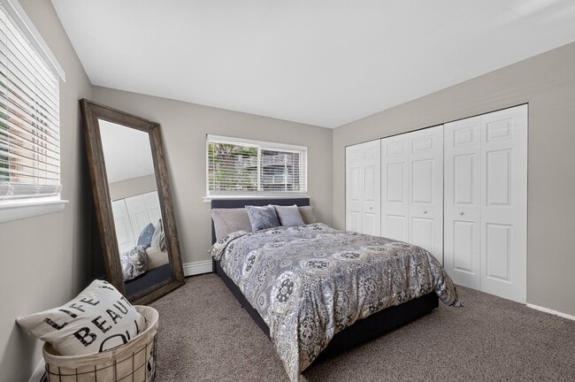 Relax in a spacious bedroom complete with a wall mirror at Renaissance at Carol Stream in Carol Stream, IL. - Renaissance at Carol Stream