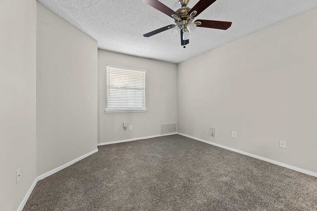 Vacant bedroom with gray carpet, ceiling fan with light, window with blinds, and textured ceiling - Walnut Creek