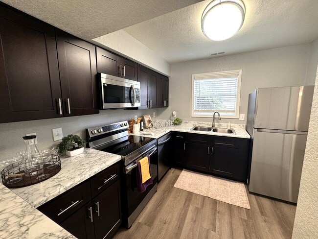 Fully equipped kitchen with stainless steel appliances and natural lighting - Devon Pointe Apartments and Townhomes