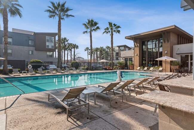 Aspire Apartments Tracy California Luxury Living A large swimming pool in front of a building with palm trees. - Aspire Apartments