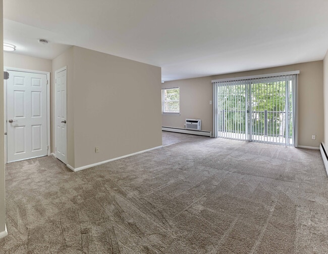 Expansive living area with wall-to-wall carpet and private balcony at Maple Terrace Apartments in Maple Shade, NJ - Maple Terrace