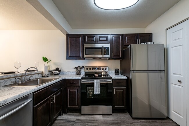 Fully equipped kitchen with stainless steel appliances and luxury vinyl flooring - Shadowmoss Pointe Apartments and Townhomes