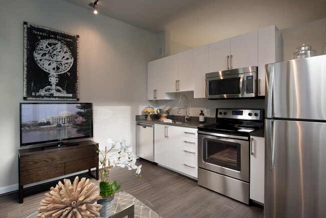 Open concept kitchen with white cabinetry, quartz countertops, stainless-steel appliances and hard surface flooring - Avalon Dunn Loring