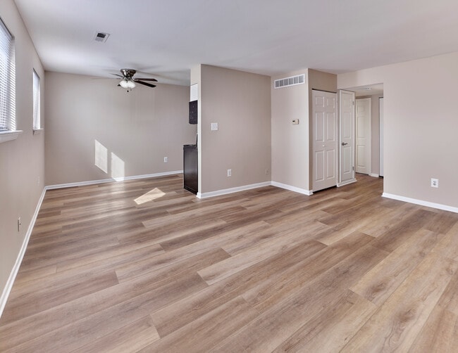 Modern open-concept living and dining space with stylish plank flooring at Village Square. - Village Square